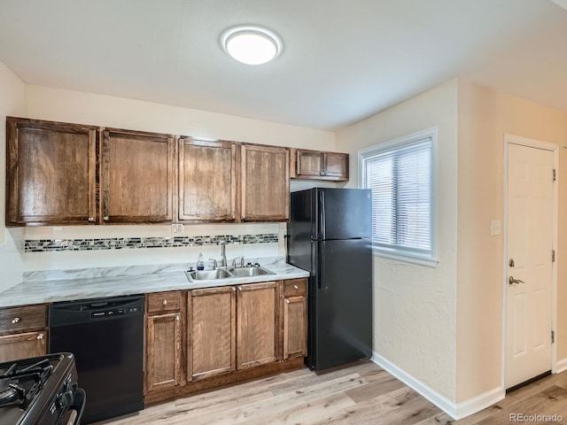 kitchen featuring light stone countertops, sink, black appliances, and light hardwood / wood-style floors