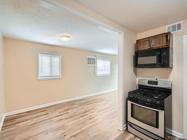 kitchen featuring light hardwood / wood-style floors, a textured ceiling, and stainless steel range with gas stovetop