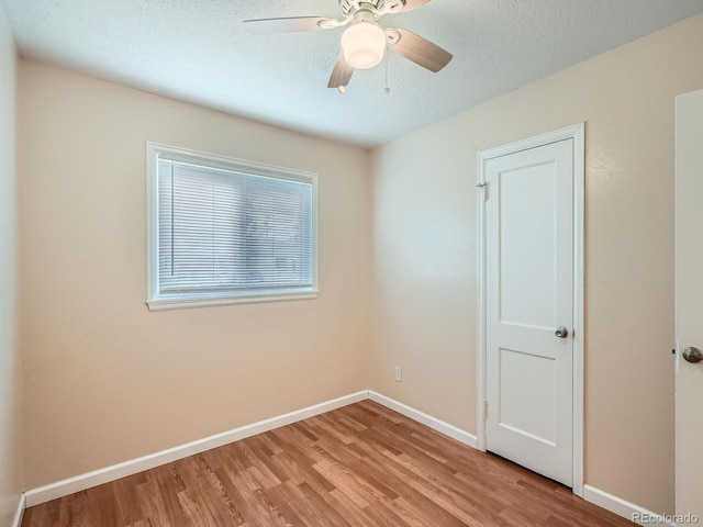 unfurnished room with a textured ceiling, light wood-type flooring, and ceiling fan