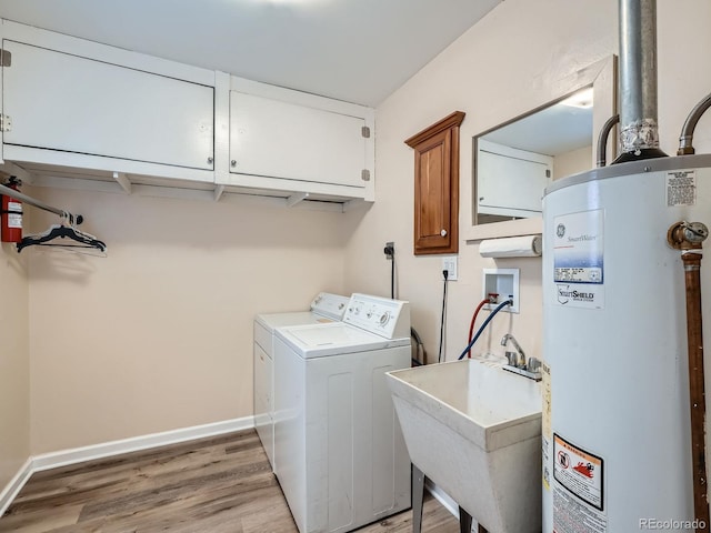 laundry area with cabinets, sink, washer and dryer, water heater, and light hardwood / wood-style flooring