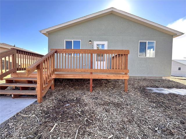 rear view of house featuring a deck and stucco siding