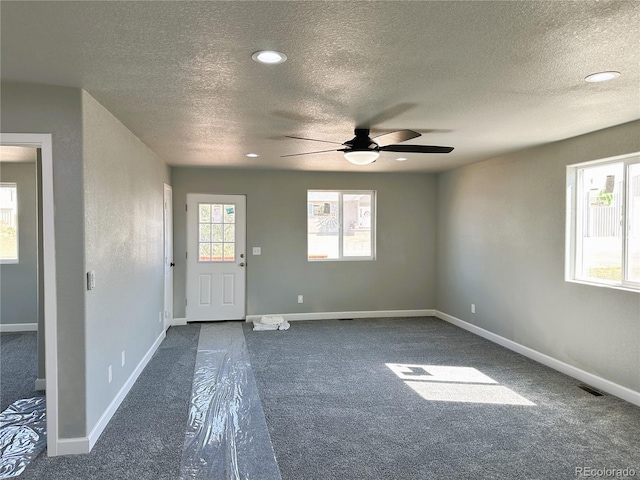 entryway with a textured ceiling, dark colored carpet, recessed lighting, and baseboards