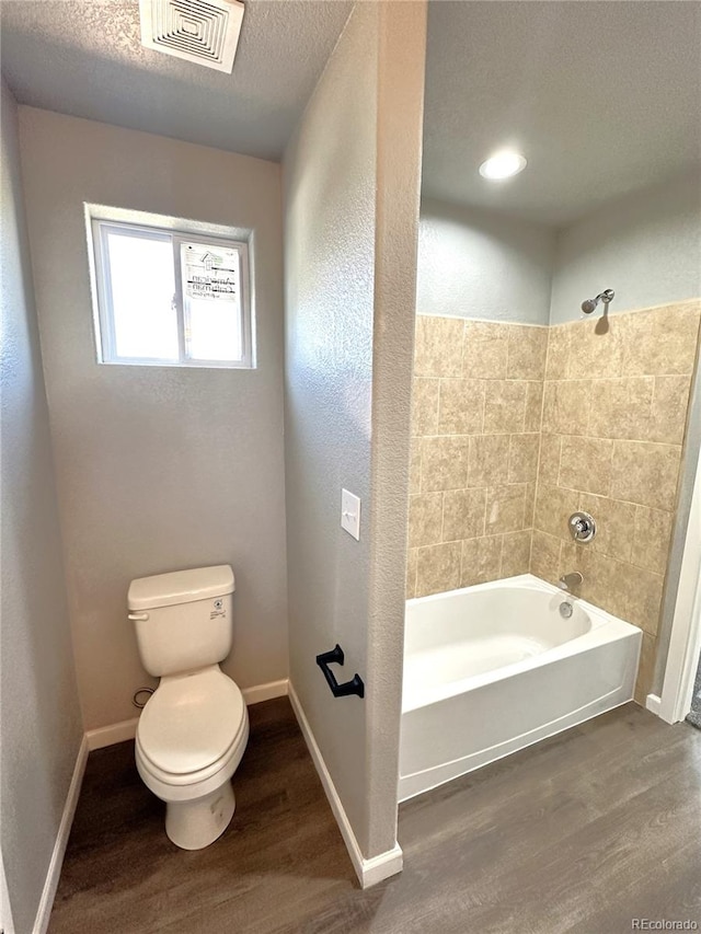 bathroom with visible vents, toilet, a textured ceiling, wood finished floors, and baseboards