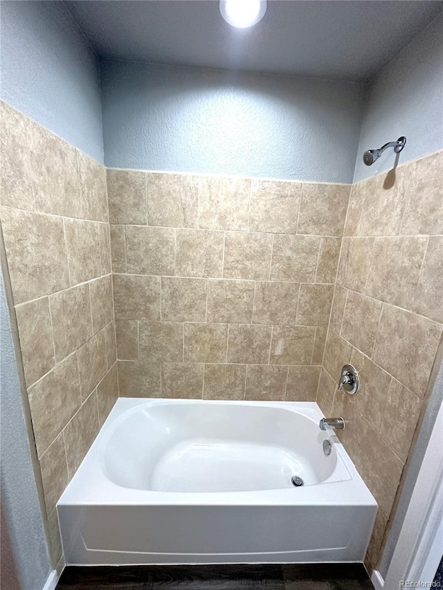 full bath with a textured wall and shower / tub combination