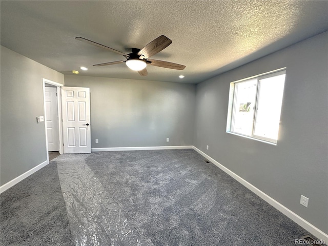 spare room with ceiling fan, baseboards, dark colored carpet, and a textured ceiling