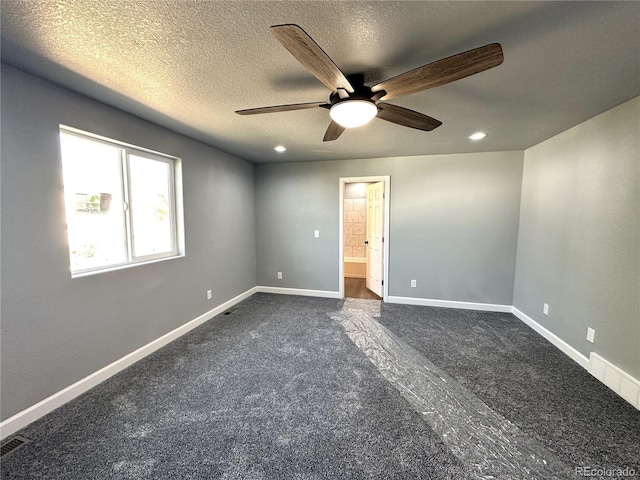 unfurnished bedroom with visible vents, baseboards, dark carpet, and a textured ceiling