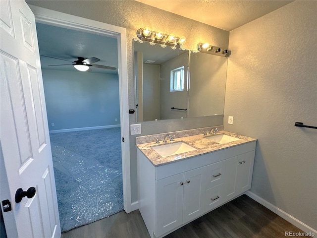 full bathroom with double vanity, a sink, baseboards, and wood finished floors