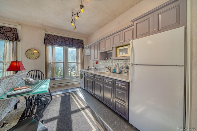 kitchen with decorative backsplash, gray cabinetry, sink, and white refrigerator