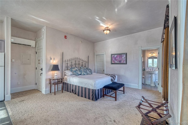 carpeted bedroom with white refrigerator, sink, a wall mounted AC, and ensuite bath