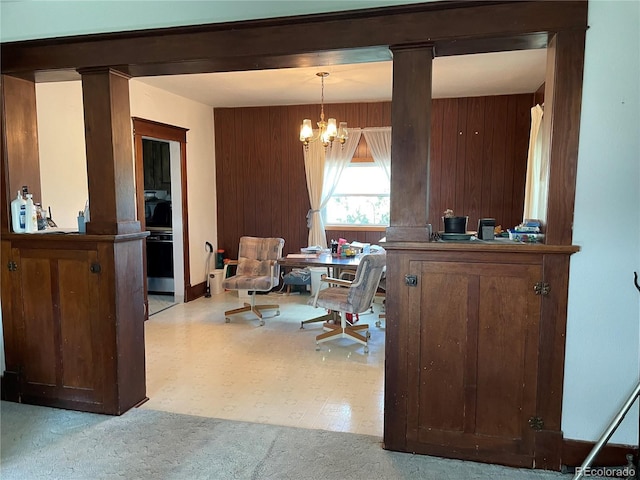 117 Lincoln Ave, Arriba, CO 80804 - dining room with a chandelier, a desk, wooden walls, ornate columns, and light carpet