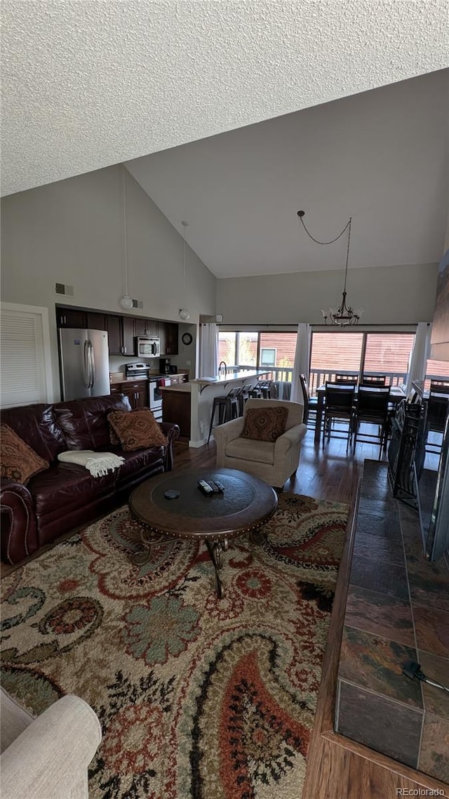 2710 Ryan Gulch Rd Unit 2731, Silverthorne, CO 80498 - living area featuring high vaulted ceiling, dark wood-style floors, a textured ceiling, and a chandelier