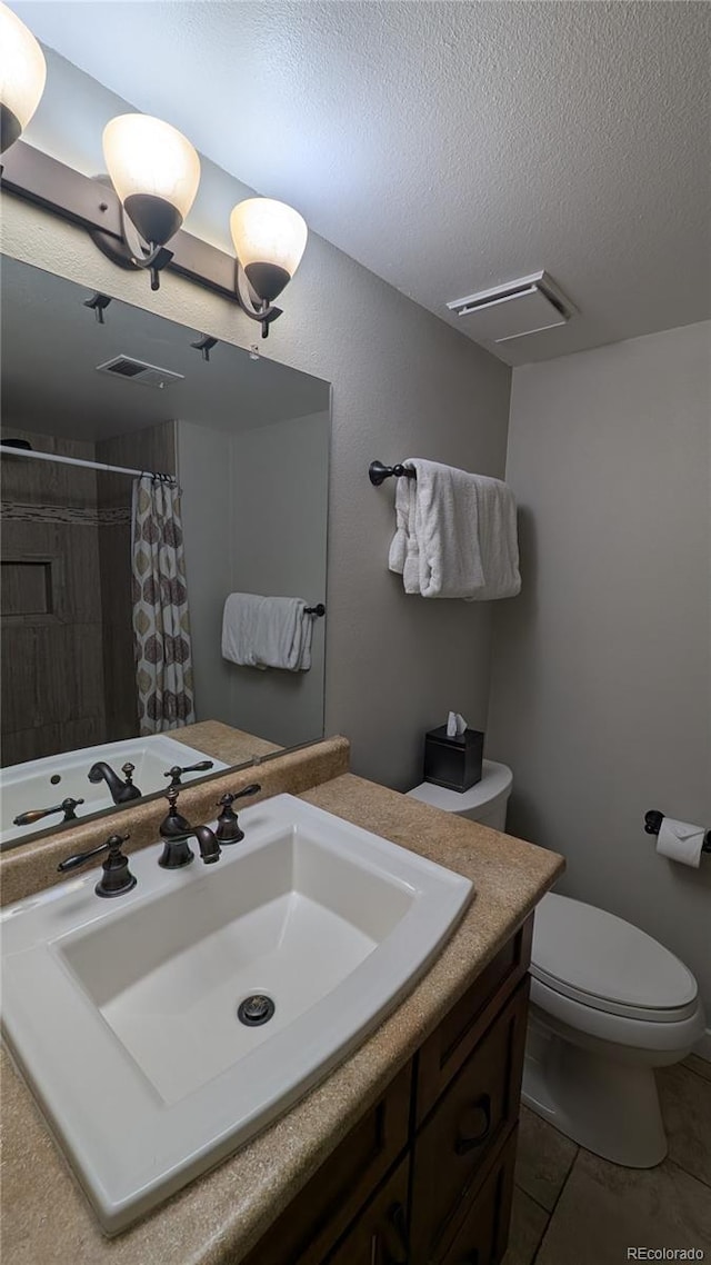 2710 Ryan Gulch Rd Unit 2731, Silverthorne, CO 80498 - bathroom with vanity, toilet, a textured ceiling, tiled shower, and tile patterned flooring