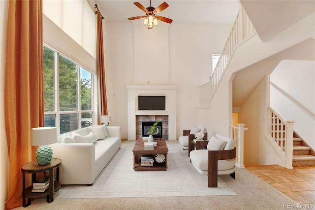 tiled living room with a tiled fireplace, a high ceiling, and ceiling fan