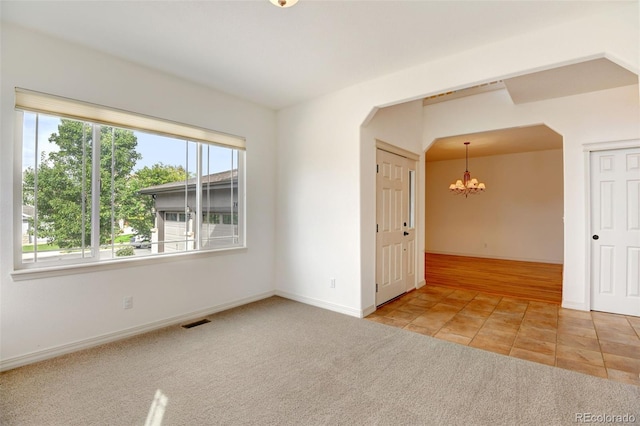 carpeted spare room featuring a notable chandelier