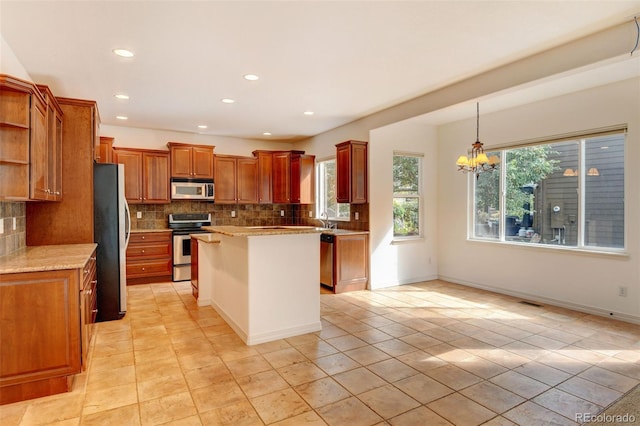 kitchen featuring hanging light fixtures, backsplash, a center island, an inviting chandelier, and appliances with stainless steel finishes