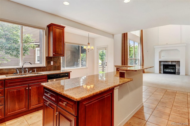 kitchen with a wealth of natural light, sink, decorative light fixtures, and a fireplace