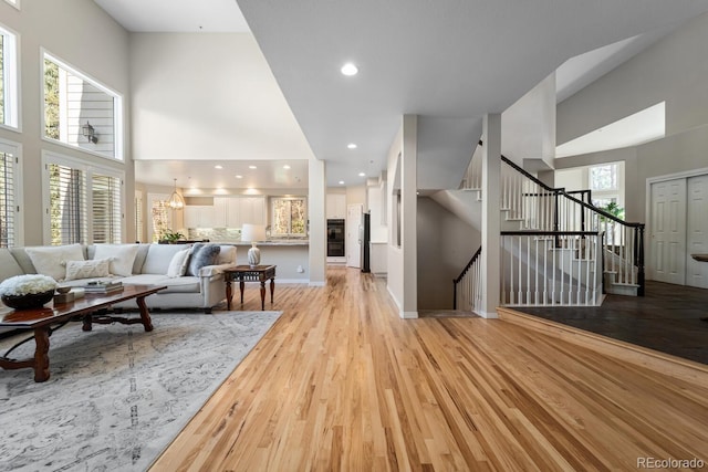 living room featuring a high ceiling, an inviting chandelier, and light wood-type flooring