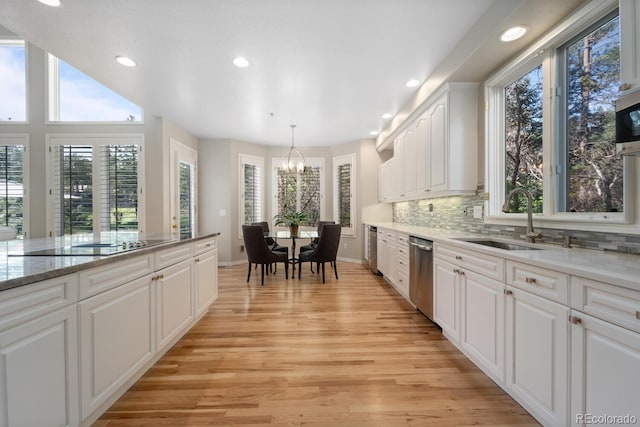 kitchen featuring pendant lighting, white cabinetry, light hardwood / wood-style flooring, sink, and light stone countertops