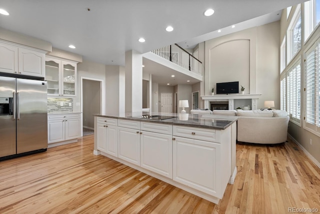 kitchen featuring light wood-type flooring, dark stone counters, stainless steel fridge with ice dispenser, and white cabinetry