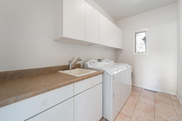 clothes washing area with cabinets, light tile patterned floors, independent washer and dryer, and sink