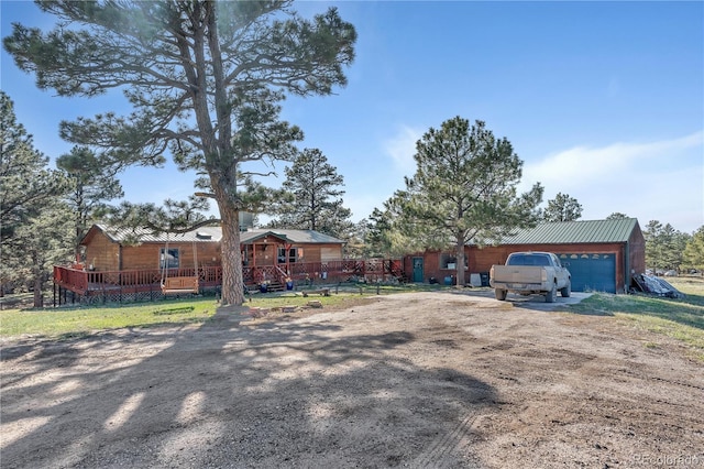 ranch-style home with a garage, dirt driveway, and metal roof