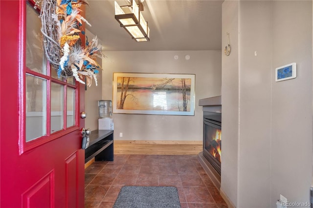 entrance foyer with baseboards and a glass covered fireplace