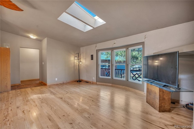 unfurnished living room featuring hardwood / wood-style flooring, baseboards, and lofted ceiling with skylight