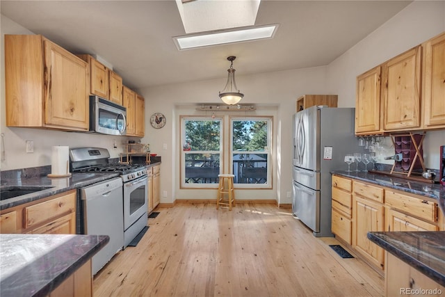 kitchen with vaulted ceiling with skylight, light wood-type flooring, hanging light fixtures, and stainless steel appliances