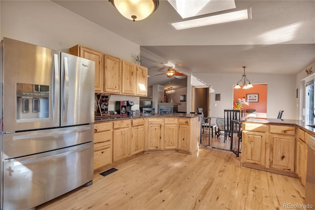kitchen featuring a peninsula, light wood-style flooring, dark countertops, light brown cabinets, and appliances with stainless steel finishes
