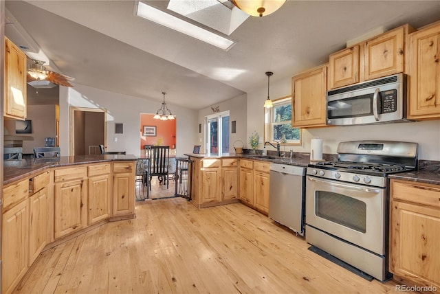 kitchen featuring a peninsula, dark countertops, appliances with stainless steel finishes, and light brown cabinets