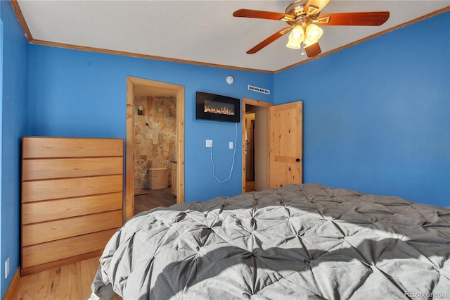 bedroom with visible vents, ceiling fan, wood finished floors, and ornamental molding