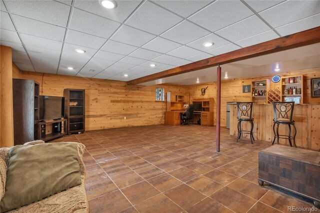living room with dark tile patterned floors, wood walls, and recessed lighting