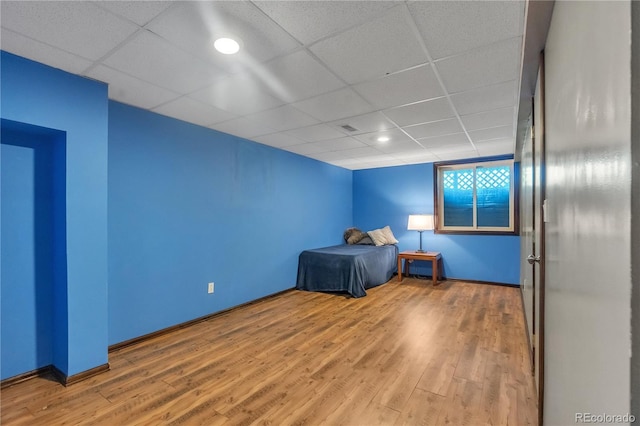 unfurnished bedroom with visible vents, baseboards, wood finished floors, and a drop ceiling