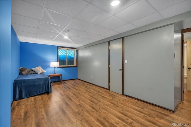bedroom with visible vents, baseboards, a paneled ceiling, and wood finished floors