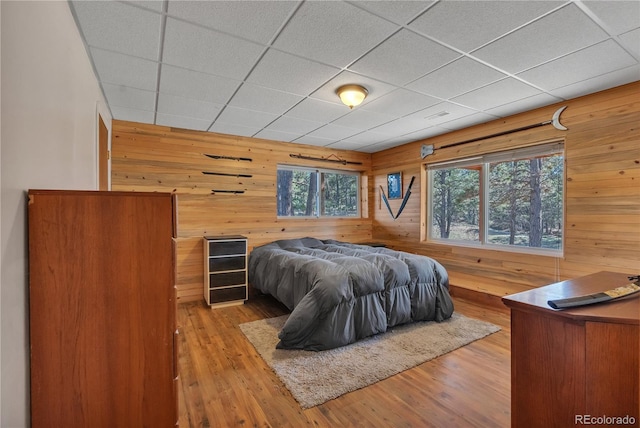 bedroom with wood finished floors, wooden walls, and a paneled ceiling