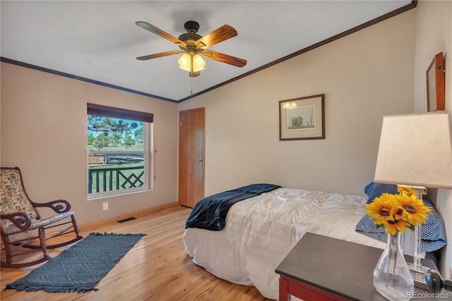 bedroom with light wood-style floors, visible vents, baseboards, and ornamental molding