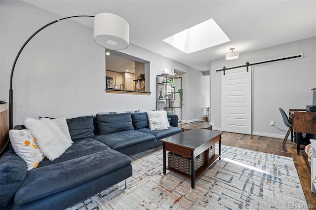 living area with a barn door, wood finished floors, baseboards, and a skylight