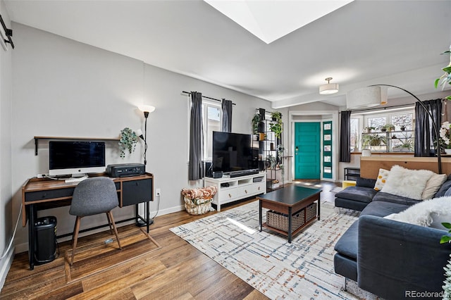 living area featuring a skylight, baseboards, and wood finished floors