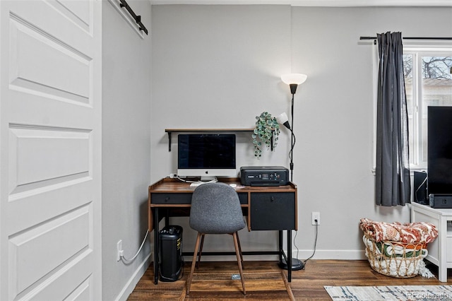 office featuring a barn door, baseboards, and dark wood-type flooring