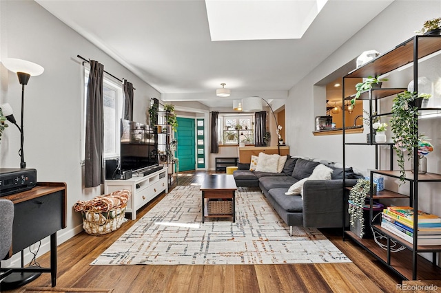 living room featuring a skylight, baseboards, and wood finished floors