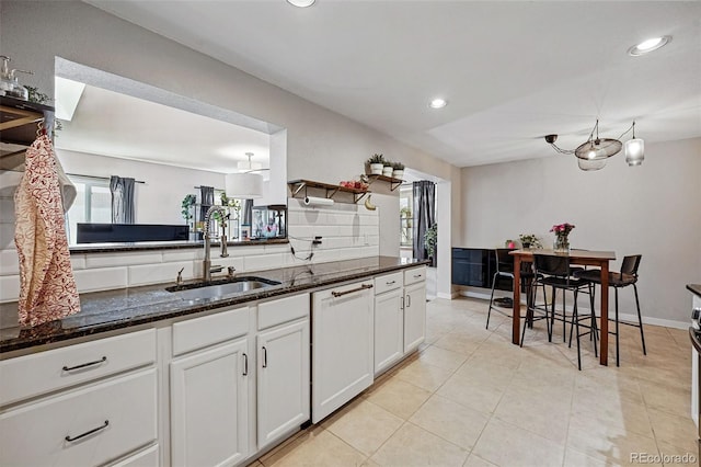 kitchen with white cabinetry, paneled dishwasher, a wealth of natural light, and a sink