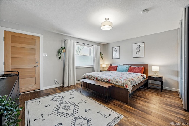 bedroom with baseboards, a textured ceiling, and wood finished floors