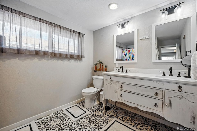 full bath featuring a textured wall, toilet, baseboards, and a sink