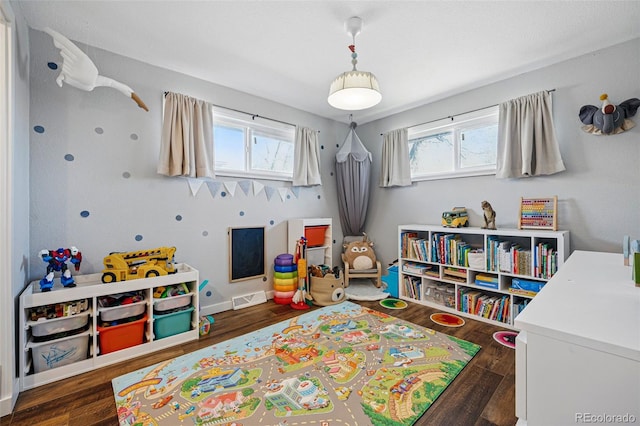 recreation room featuring wood finished floors, visible vents, a wealth of natural light, and baseboards