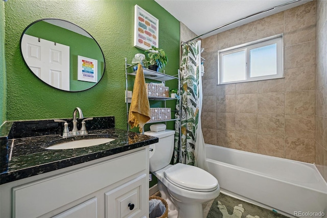 bathroom featuring toilet, shower / bath combination with curtain, vanity, and a textured wall