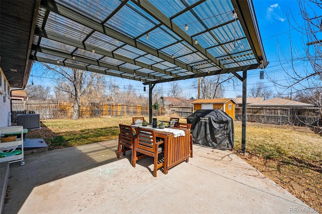 view of patio / terrace with an outbuilding, outdoor dining space, central AC, and a fenced backyard