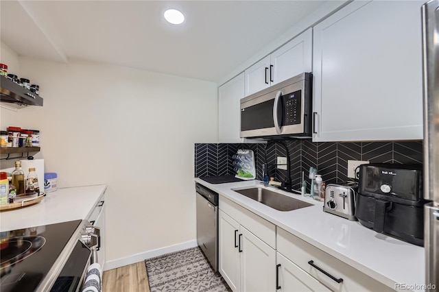 12131 Melody Dr Unit 201, Denver, CO 80234 - kitchen featuring stainless steel appliances, white cabinets, light countertops, decorative backsplash, and light wood-style flooring