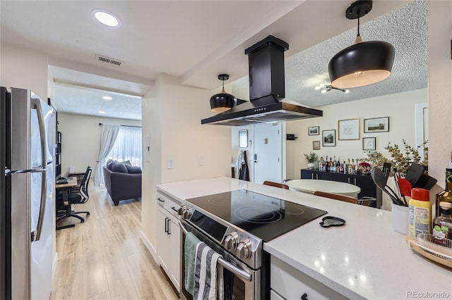 12131 Melody Dr Unit 201, Denver, CO 80234 - kitchen featuring appliances with stainless steel finishes, island exhaust hood, white cabinetry, light wood finished floors, and decorative light fixtures