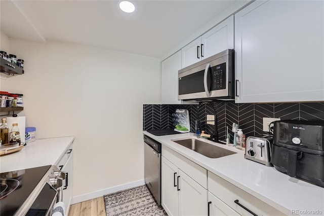 12131 Melody Dr Unit 201, Denver, CO 80234 - kitchen with appliances with stainless steel finishes, tasteful backsplash, white cabinetry, and light countertops