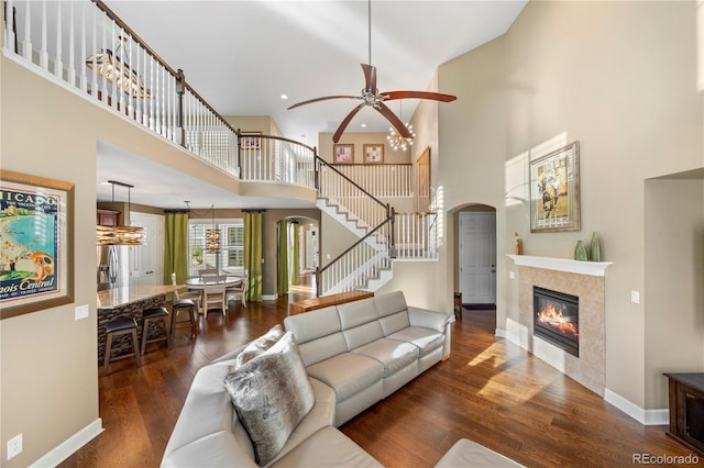 1133 Lucky Ct, Castle Rock, CO 80109 - living room featuring arched walkways, a high ceiling, a ceiling fan, stairway, and a tile fireplace